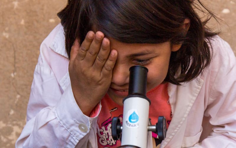 niña alizando con microscopio la limpieza del agua